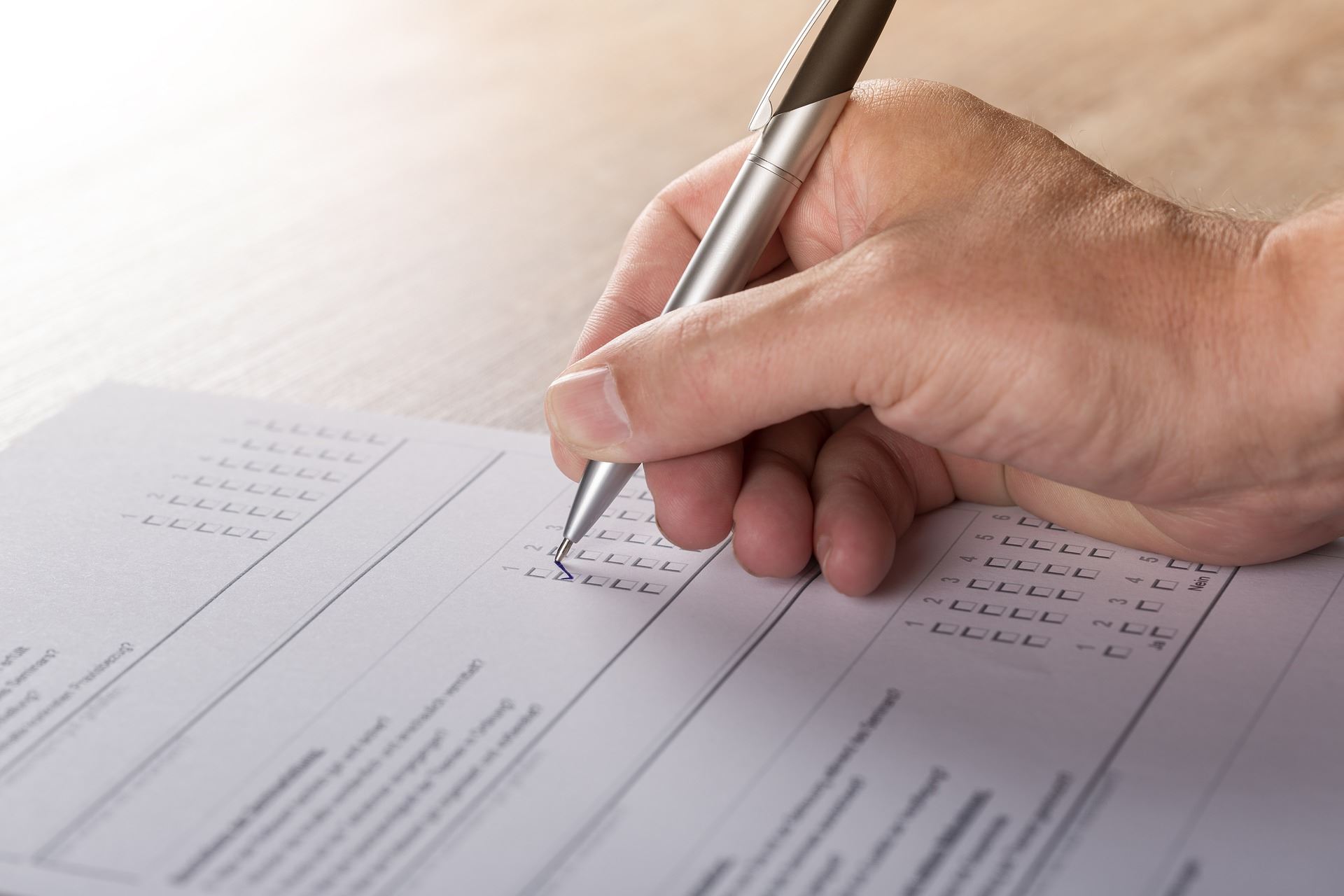 Person filling out survey with pen and paper